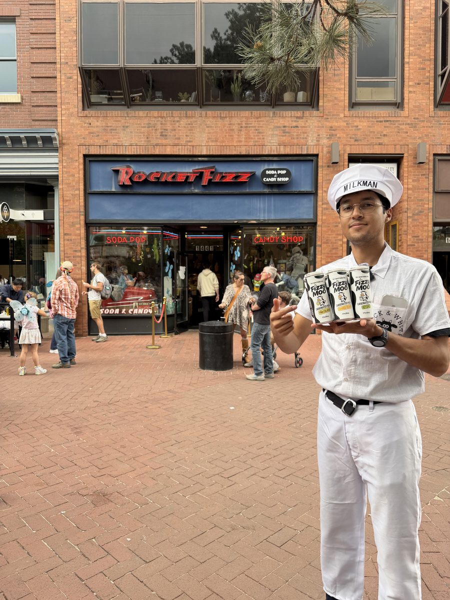 The Fizzy Moo milkman holding cans in front of Rocket Fizz on Pearl Street